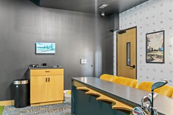 A room with a grey wall and a wooden cabinet.